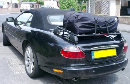 black jagaur xk8 convertible with a black luggage rack fitted with a boot-bag on it