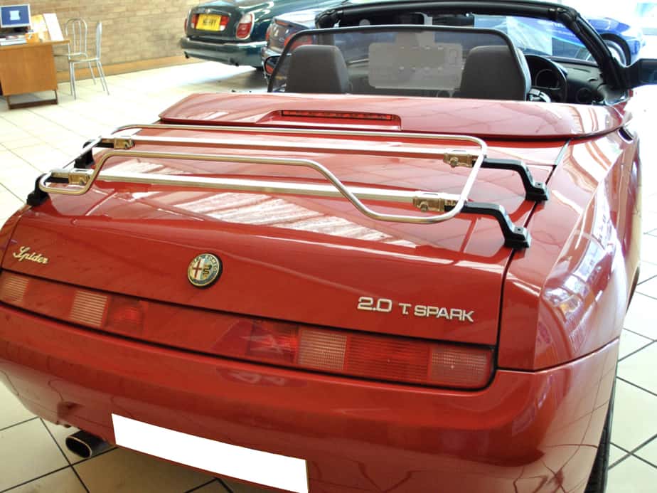 red alfa romeo 916 spider in a car showroom with a stainless steel boot rack fitted