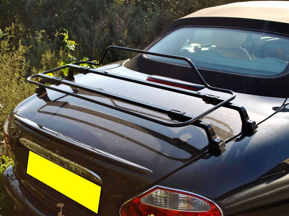 black jaguar xk8 cabriolet with a black boot rack fitted next to a hedge on a sunny day