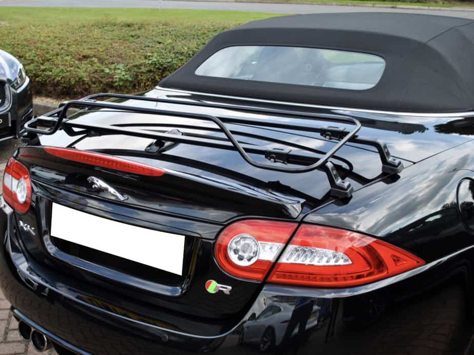 Black jaguar xk convertible with the hood up and a black luggage rack fitted to the boot