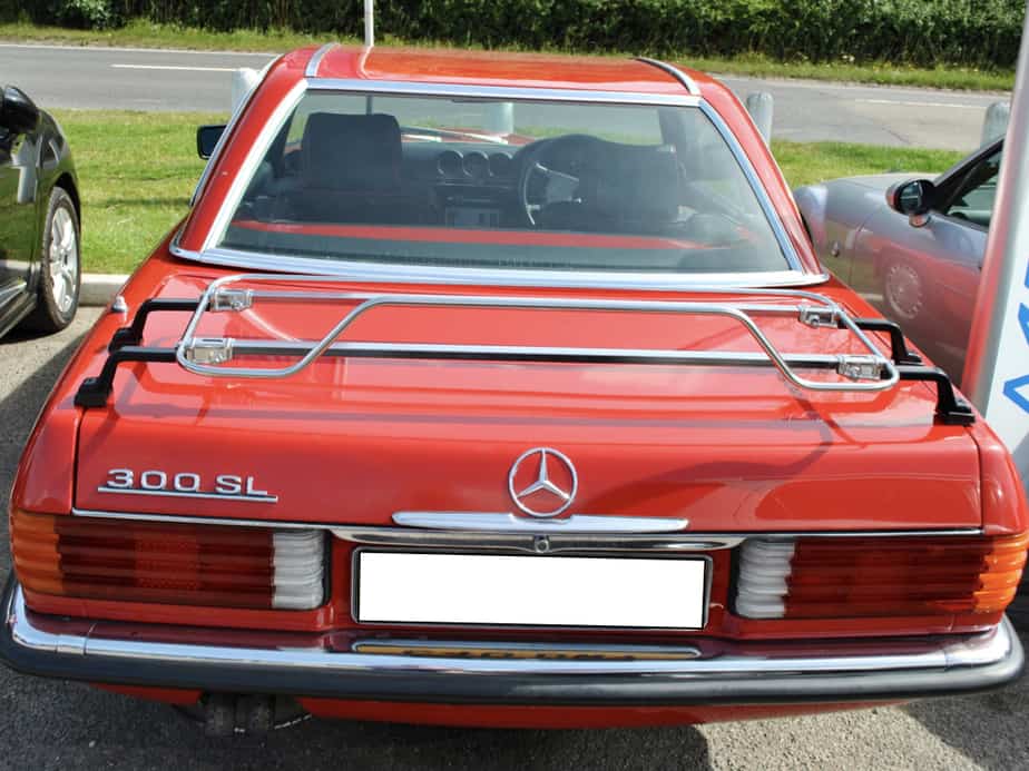 red mercedes sl r107 on a sunny day with a hard top fitted and stainless steel boot rack on the boot