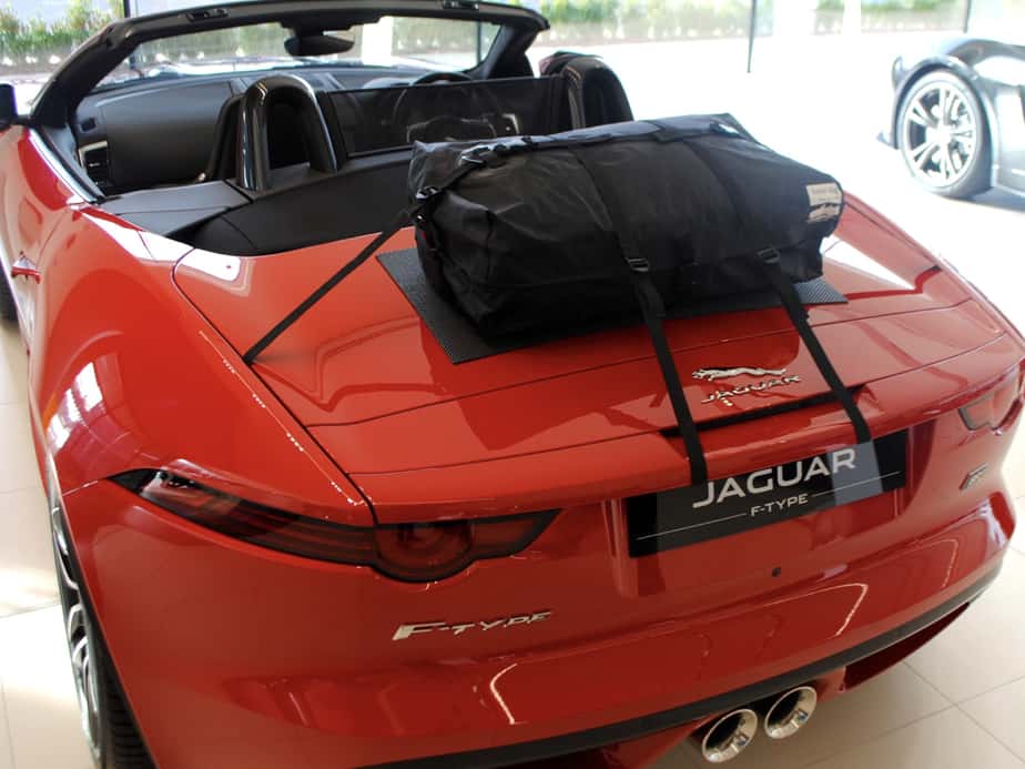 Red jaguar f type convertible with the hood down and a boot-bag original boot rack fitted in a jaguar showroom