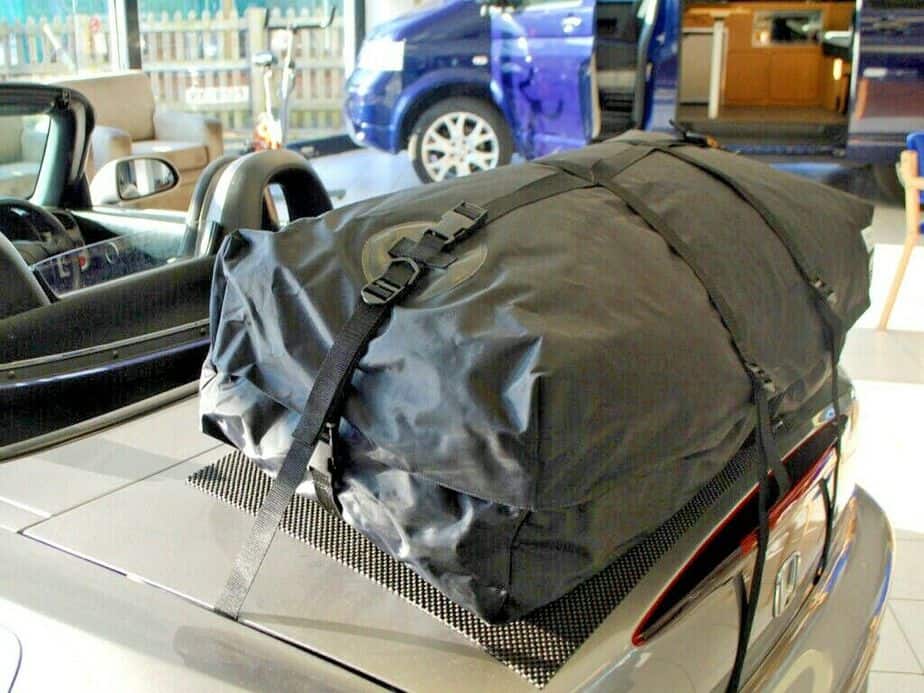 side view of a honda s2000 with a boot-bag vacation luggage rack fitted in a showroom with the hood down.
