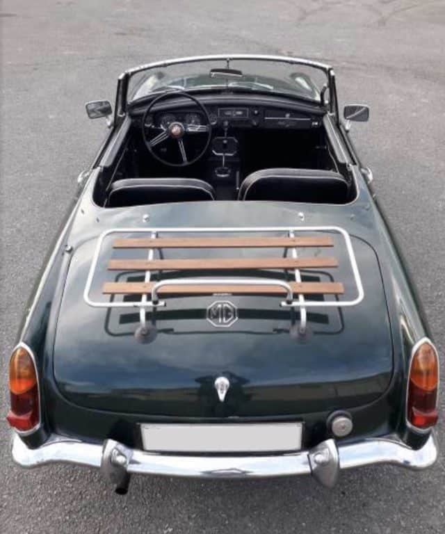 green mgb with a wood and chrome boot rack fitted with the hood down