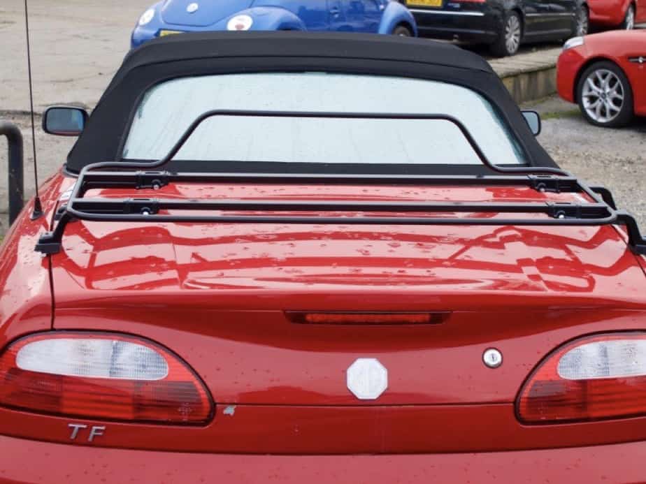 red mg tf roadster with a black boot rack fitted in a car park on a cloudy day