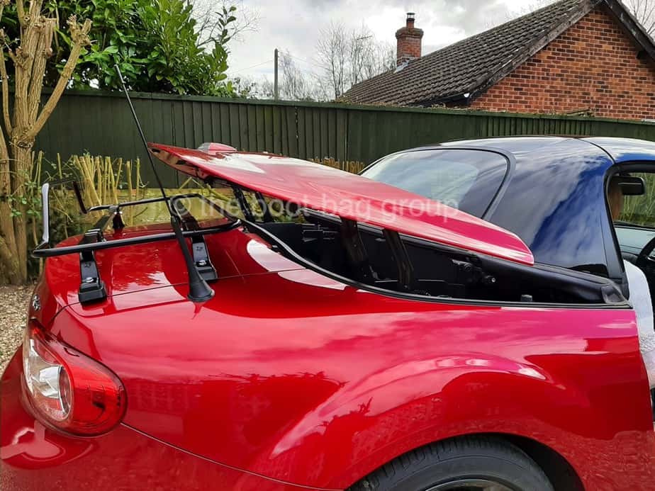 side view of a mazda mx5 roadster coupe with a bot rack fitted and the roof operating