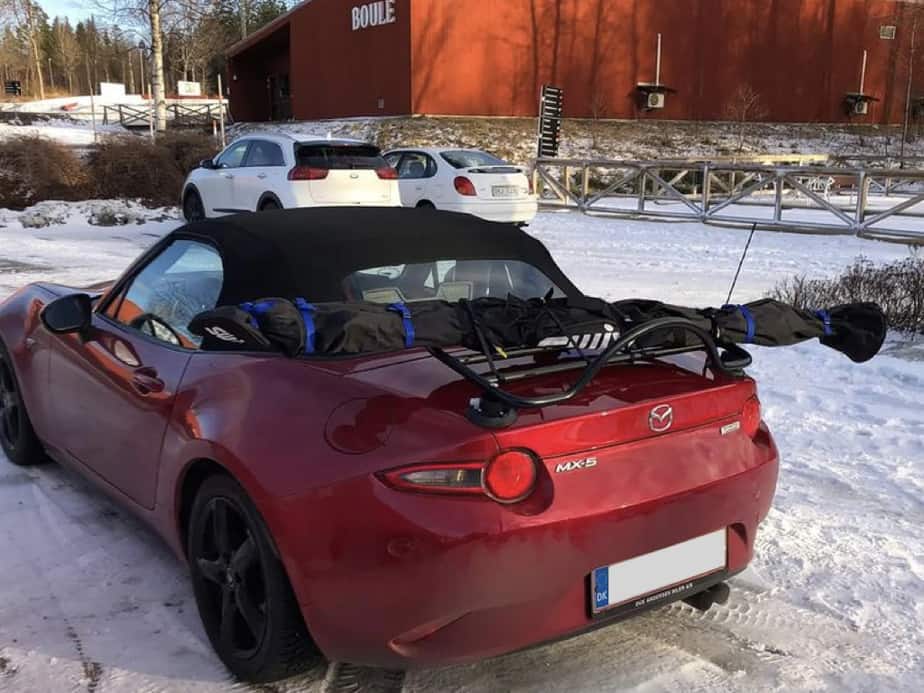 red mazda mx5 mk4 with a boot rack fitted carrying ski's in the snow