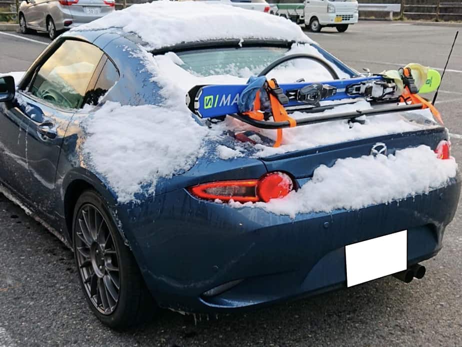 blue mazda mx5 rf with a luggage rack fitted carrying skis with snow on the car