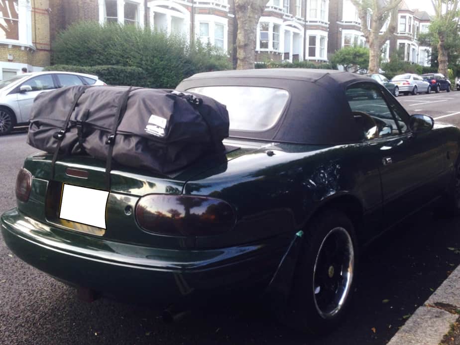 green mazda mx5 mk1 with a boot-bag boot rack fitted on a residential street