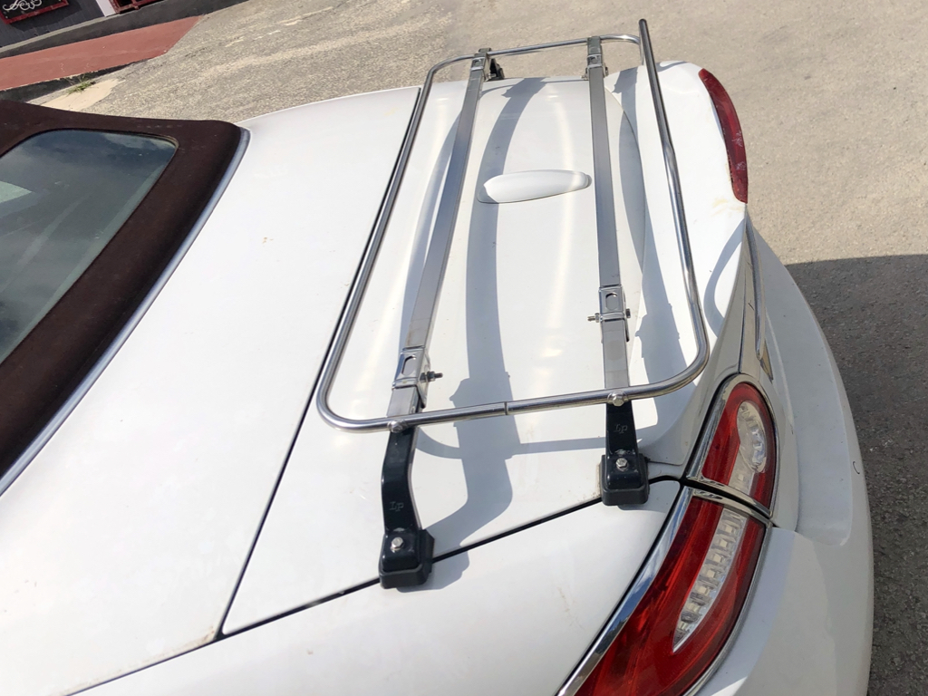 white Jaguar xk convertible with a stainless steel luggage rack fitted tot he boot photographed close from the side