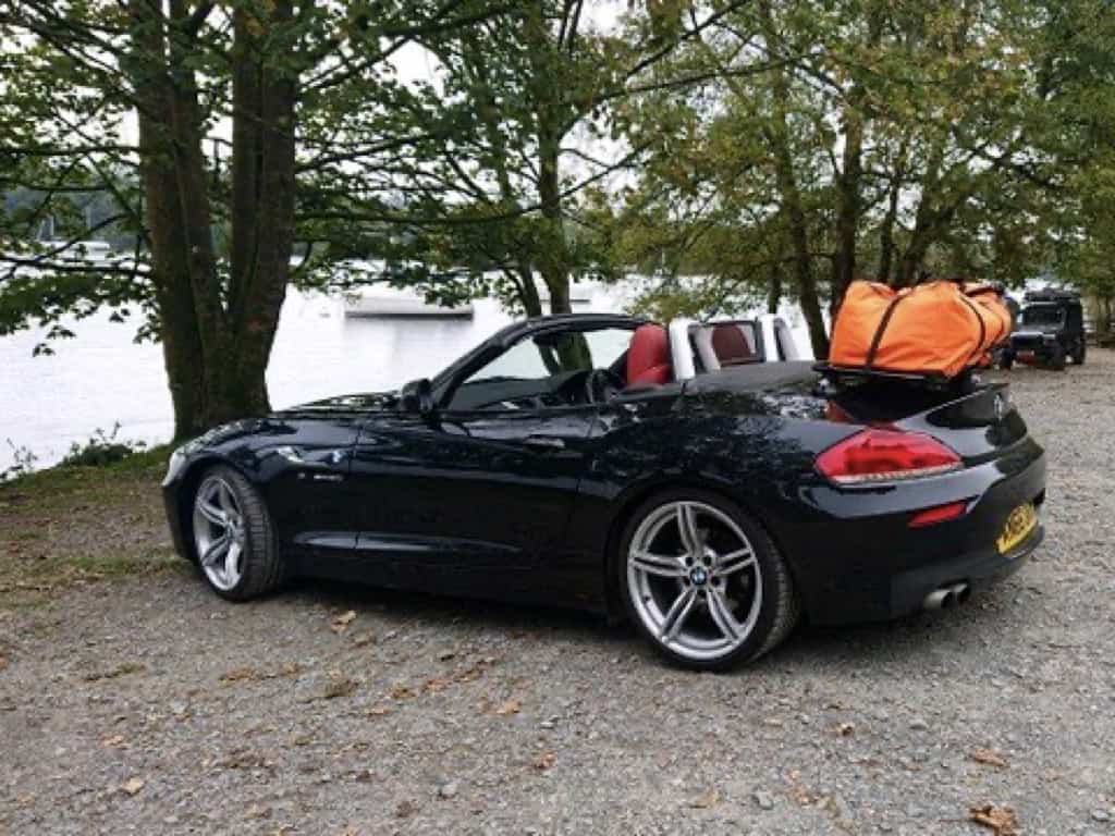 black bmw z4 e89 with a revo-rack luggage rack fitted carrying a large orange bag next to a lake