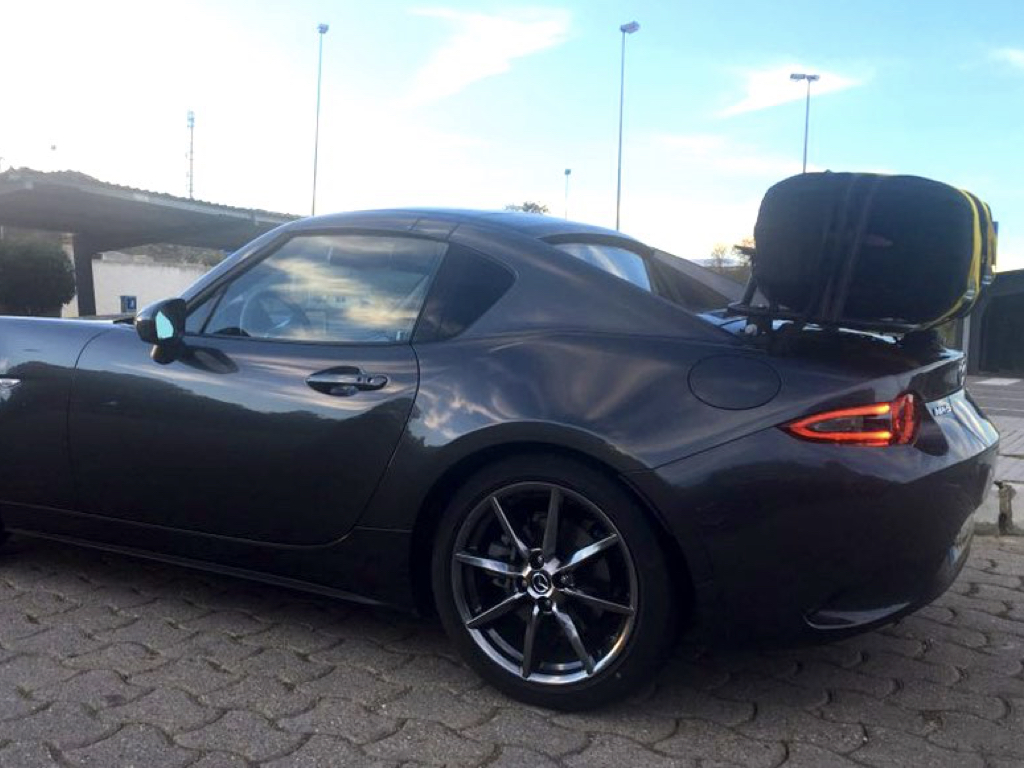 black mazda mx5 rf with a boot rack fitted carrying a large black case
