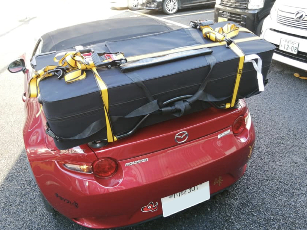 red mazda mx5 nd with a boot rack fitted carrying a large black case
