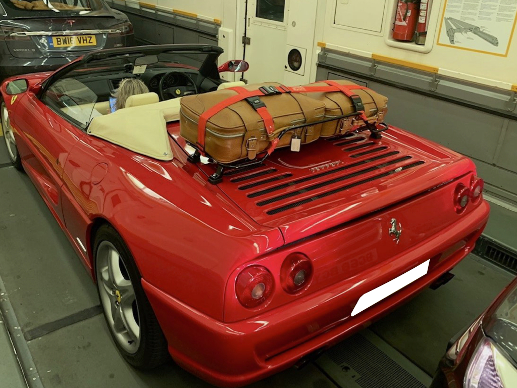 red ferrari 355 convertible on the channel tunnel roof down with a luggage rack fitted carrying two brown suitcases